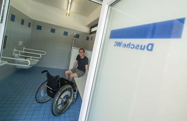 Rollstuhlfahrer sitzt in barrierefreier Umkleidekabine