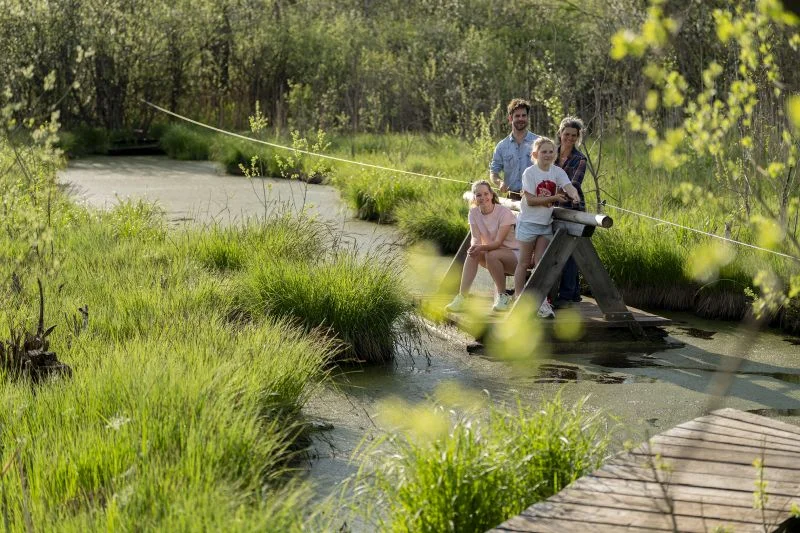 Familie fährt auf einem Floß über ein Moorgewässer